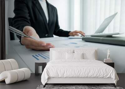 The hands of a male businesswoman are analyzing and calculating the annual income and expenses in a financial graph that shows results To summarize balances overall in office Wall mural