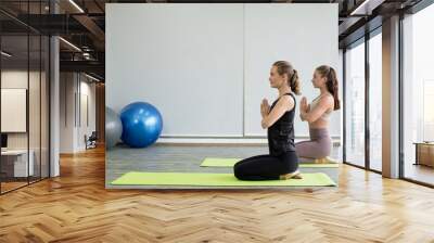 Two young women play yoga stretching, exercise for health in fitness, the concept of physical and mental health care Wall mural