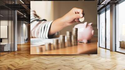 Woman's hand. putting coins in the piggy bank with coins, saving money with coins, stepping into a successful growing business, and saving for thought in retirement. Retirement savings concept Wall mural