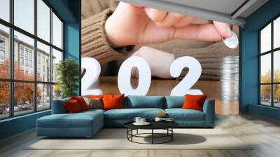 2021 New year saving money and financial planning concept. Female hands putting coins on stack with number 2021. Creative idea for business growth, tax payment, investment and banking. Wall mural