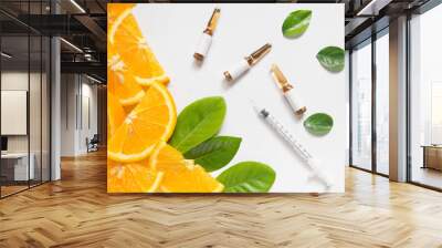 Top view of vitamin C brown ampule for injection and syringe with fresh juicy orange fruit slice and green leaves on white table. Vitamin/mineral supplement concept. Beauty product mock-up. Wall mural