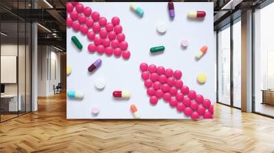 two pink arrows made by pills among many different medical tablets/capsules on blue tone background. Wall mural