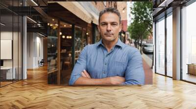 A man in apron stands in front of a his restaurant. He looks serious and focused Wall mural