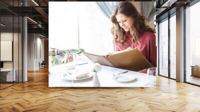 A woman in a restaurant with the menu in hands Wall mural