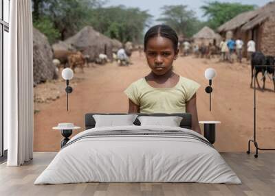 A young african american preteen girl stands in front of a dirt road in a village. The girl has hair in a braid. Wall mural