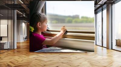 Happy little girl traveling by train. She is lokking through the window Wall mural