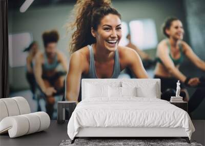 sporty girl riding indoor stationary bike during cycling class with her female friends in cycling studio. Wall mural