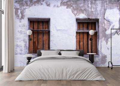 Two windows boarded up by wooden planks in a brick wall of an old building close up Wall mural