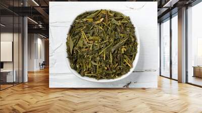 Green tea leaves bancha in white bowl on wooden background. Wall mural