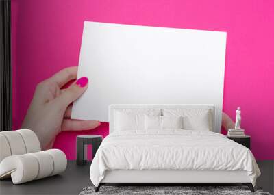 Female hand holds one blank sheet A5 poster on pink background Wall mural