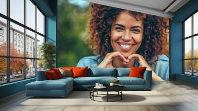 ortrait photography of a beautiful woman smiling and making the shape of a heart with her hands, close-up view Wall mural