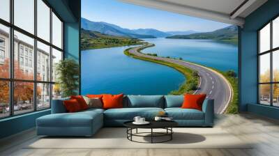 A circular asphalt road wraps around a lake under a clear blue sky Wall mural