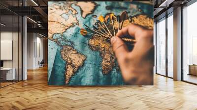 A man's hand holding darts pointed at a world map, symbolizing global travel connections and navigation, with an emphasis on destination points and business planning, depicted as a GPS navigator Wall mural