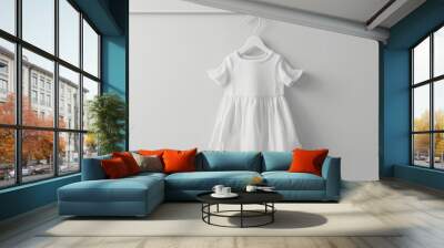 A mockup of a white baby cotton dress on a white background, ready for design previews, displayed on a white hanger Wall mural