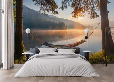 A serene summer camping scene at a lake, featuring an empty hammock between two trees with a view of a foggy mountain lake at sunrise. The scene promotes an outdoor and adventure theme Wall mural