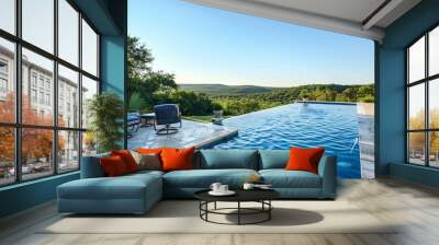 An empty swimming pool with blue water and open patio chairs set against a green Texas Hill country background under a clear sky, capturing a tranquil day Wall mural