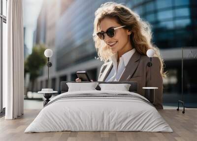 A young business woman in a suit using her cell phone on a sunny day Wall mural