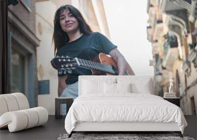 brunette woman walking with a guitar under her arm Wall mural