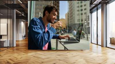 Handsome bearded hipster man use and looking at laptop computer with coffee at table in cafe. Communication and technology concept Wall mural