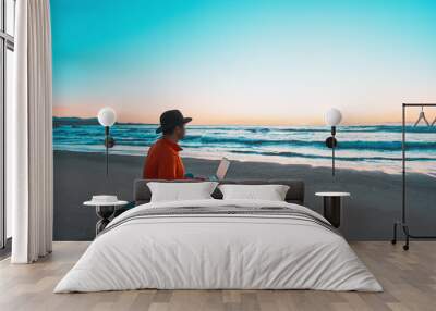 latino digital nomad sitting on the shore of the beach contemplating the sunset over the ocean Wall mural