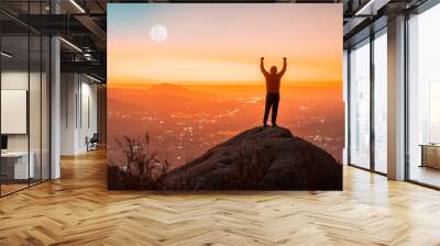 person silhouette on the top of the mountain with hands raised, back view, sunset background Wall mural