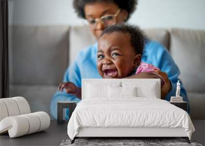 A baby crying angrily in his mother's arms Wall mural