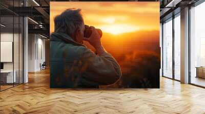 Senior man photographing a sunset with professional camera Wall mural