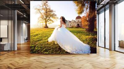 Portrait of a wedding bride posing in a white hipster style dress with flowers in her hands in the forest on sunset Wall mural