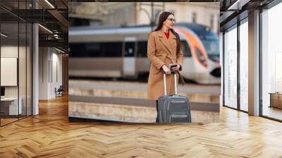 young girl standing at train station, portrait of tourist in coat Wall mural