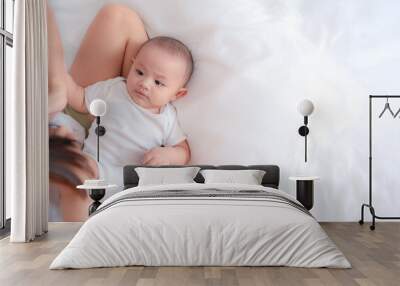 Cute Asian newborn baby boy playing on white bed with smile happy face. While your mother takes care nearby. Little innocent new infant adorable child in first day of life. Mother's Day concept. Wall mural