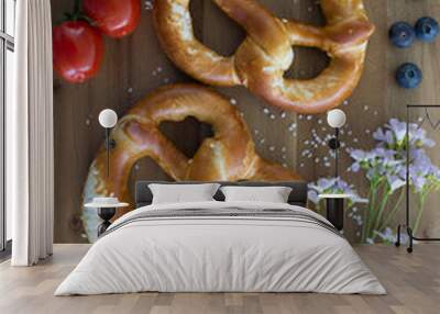 Bavarian salted sesame pretzels on table. Crispy freshly baked pretzels on the table, decorated with wildflowers, salted blueberries and fresh green bear onions. Wall mural