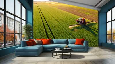 Drone shot of a tractor spraying in lush green wheat fields under the bright sun, showcasing modern agriculture Wall mural