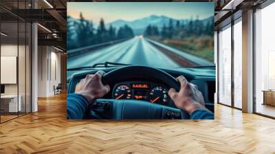 A man is driving a truck on a highway with mountains in the background Wall mural