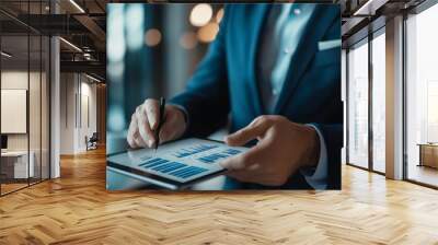 A business professional analyzes data on a tablet, surrounded by a modern office ambiance, highlighting the significance of technology in decision-making. Wall mural