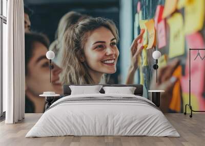 A group of young adults collaborate creatively, smiling as they engage with colorful sticky notes on a board, showcasing teamwork and brainstorming. Wall mural