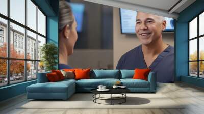 A smiling healthcare professional in scrubs converses with a patient, while medical images display in the background. Wall mural