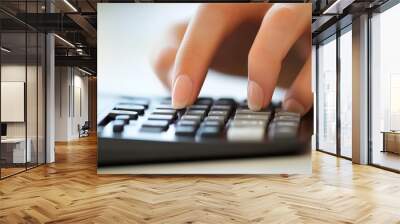 Close-up of a person using a calculator, reviewing financial documents, symbolizing financial planning and management. Wall mural