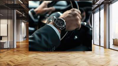 Close up of man in black suit wearing watch and keeping hand on the steering wheel while driving a luxury car. Wall mural