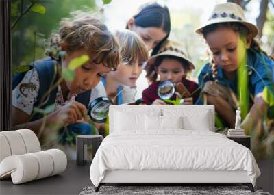 Diverse group of school children with teacher on field trip in nature exploring with magnifying glasses and notepads in hand, Learning science concept. Wall mural