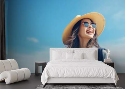 Happy young Asian tourist woman wearing beach hat, sunglasses and backpacks going to travel on holidays on blue background. Wall mural