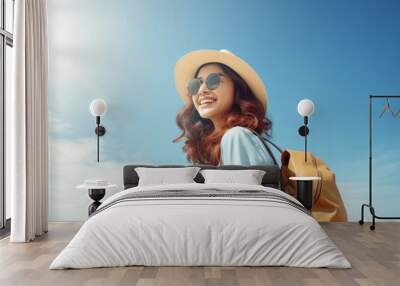 Happy young Asian tourist woman wearing beach hat, sunglasses and backpacks going to travel on holidays on blue background. Wall mural