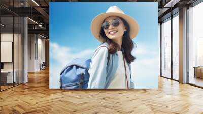 Happy young Asian tourist woman wearing beach hat, sunglasses and backpacks going to travel on holidays on blue background. Wall mural