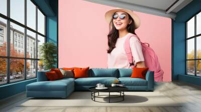 Happy young Asian tourist woman wearing beach hat, sunglasses and backpacks going to travel on holidays on pink background. Wall mural