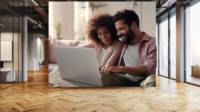 Multiracial young couple watching computer laptop on the sofa at home. Technology lifestyle concept. Wall mural