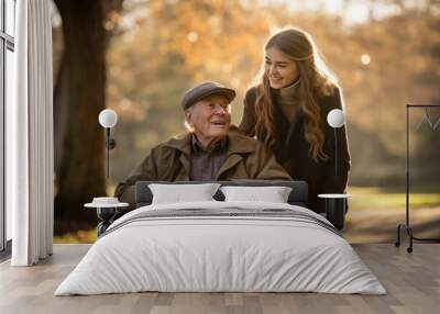 Senior man in wheelchair with his daughter standing on back for take care in autumn park Wall mural