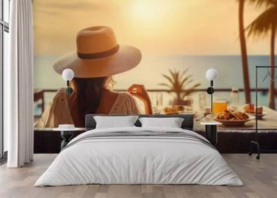 Young woman on summer vacation enjoying breakfast on a luxury hotel resort terrace overlooking the sea. Wall mural