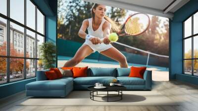 Young woman playing tennis on court Wall mural