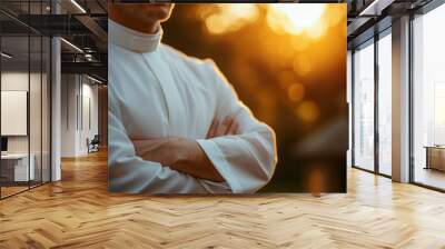 Man in White Clergy Collar with Arms Crossed, Standing in Sunlight Wall mural