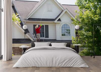 Man cleaning the upper floor exterior of his home Wall mural