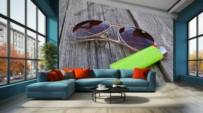 Cool pilot sun glasses isolated on a wooden table with a green lighter for smoking Wall mural